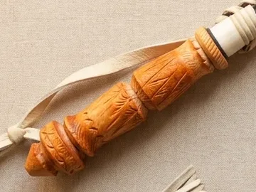 Резная точёная рукоять рыжего тона, рядом светлый кожаный темляк
